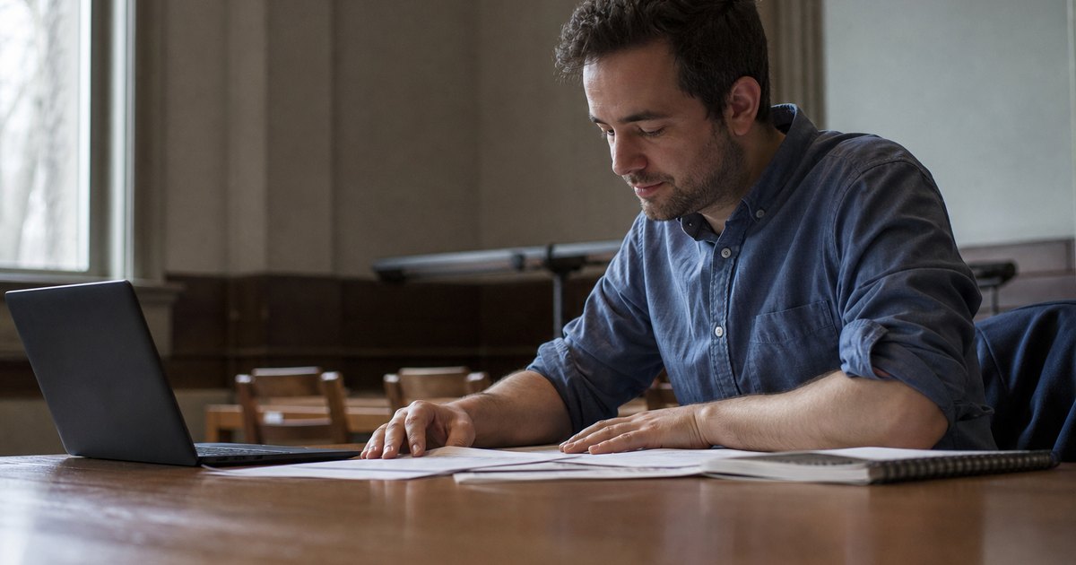 A student reviews a capstone rubric, draft, and deliverable notes beside a laptop.