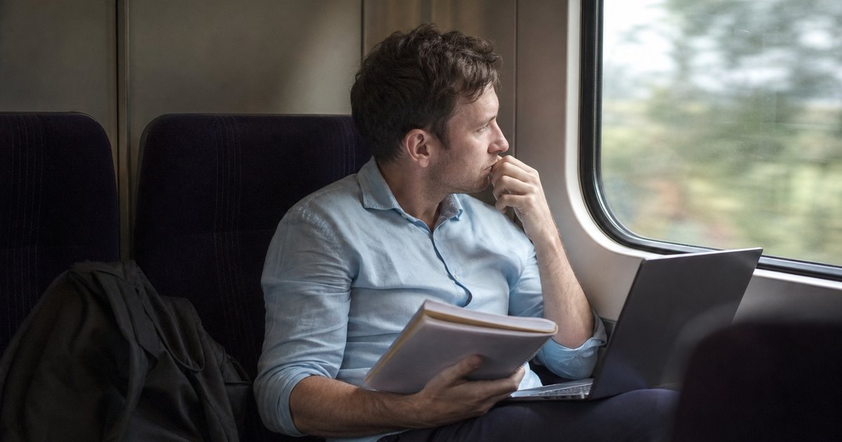 A student checks notes on a laptop while riding a train.