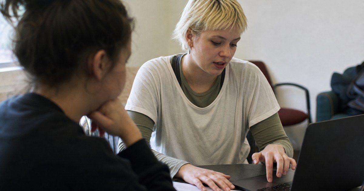 Student discussing an assignment brief with another person at a study table.