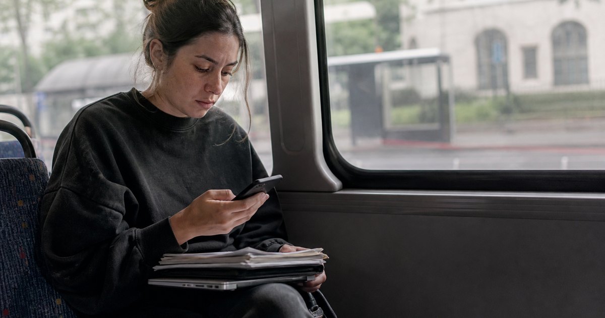 A tired doctoral student reviews deadlines and papers on her lap during a bus ride.