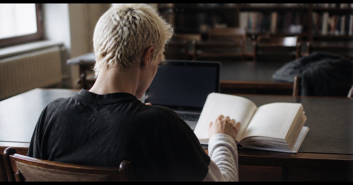 Student reviewing a thesis outline and marked-up draft at a library desk.
